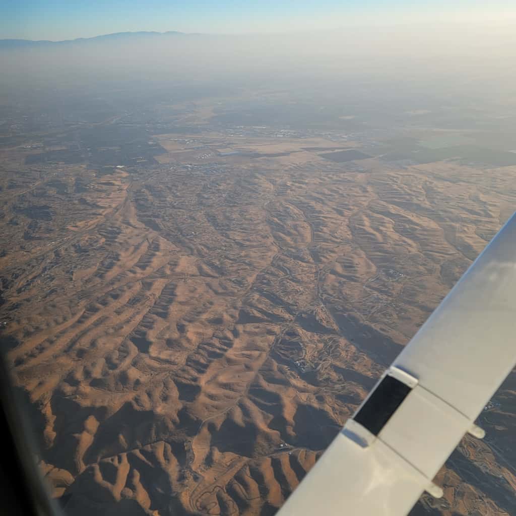 Aircraft wing at golden hour above the clouds